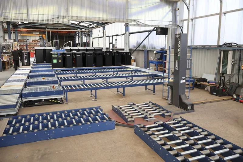 Industrial conveyor network with roller transfer sections and street furniture products in a manufacturing facility