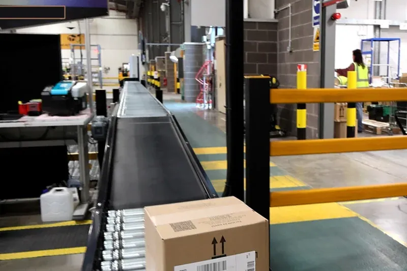 Eine Anlage mit langer Wellenrolle transportiert Kartons durch ein Distributionszentrum.