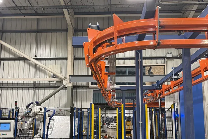 Power-and-Free-Fördersystem mit robotergestützter Fertigungsausrüstung MCM Autotrack Power and Free conveyor system installed above robotic manufacturing equipment and safety guarding
